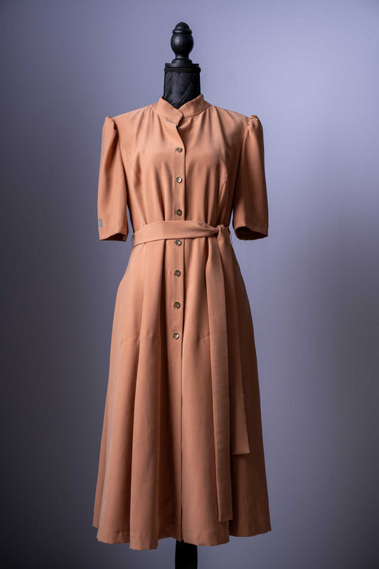 Entdecken Sie zeitlose Eleganz mit diesem klassischen Kleid in einem warmen Camel-Ton. Sein schlichtes, aber raffiniertes Design macht es zu einem vielseitigen Must-have für jede Garderobe.